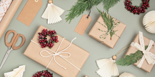 Christmas background with gift boxes and rolls of colored kraft wrapping paper. Xmas celebration, preparation for winter holidays. Festive mockup, top view, flatlay